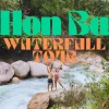 Easy Rider motorbike parked by a clear natural pool at Hon Ba Waterfall, surrounded by lush forest.