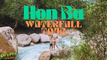 Easy Rider motorbike parked by a clear natural pool at Hon Ba Waterfall, surrounded by lush forest.