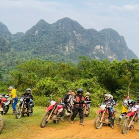 Motorcycle riders beneath limestone mountains on the 20-Day Saigon to Hanoi Vietnam Motorcycle Tour